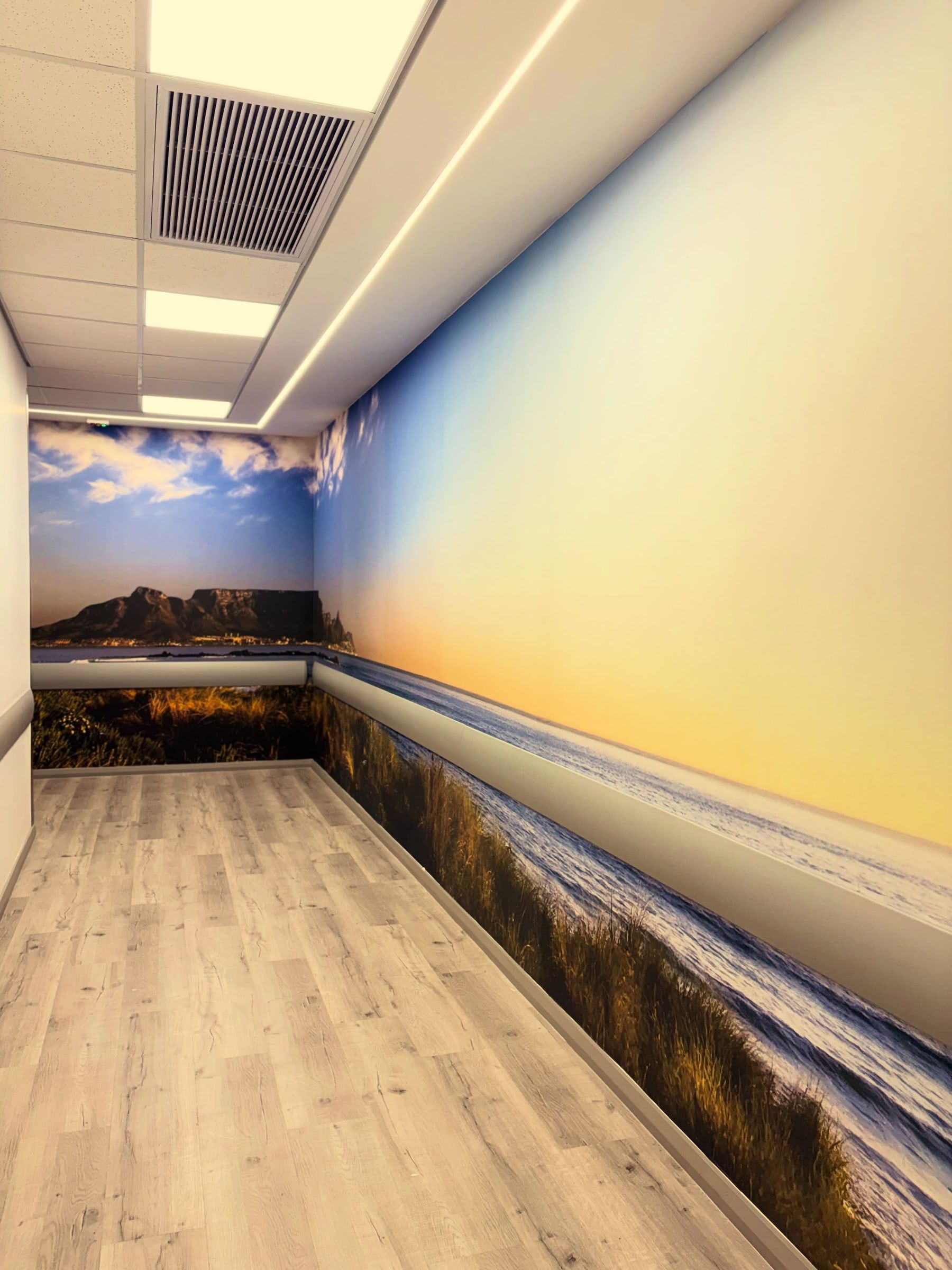 Corridor wrapped in a beach and sunset mural with Table Mountain at the far end