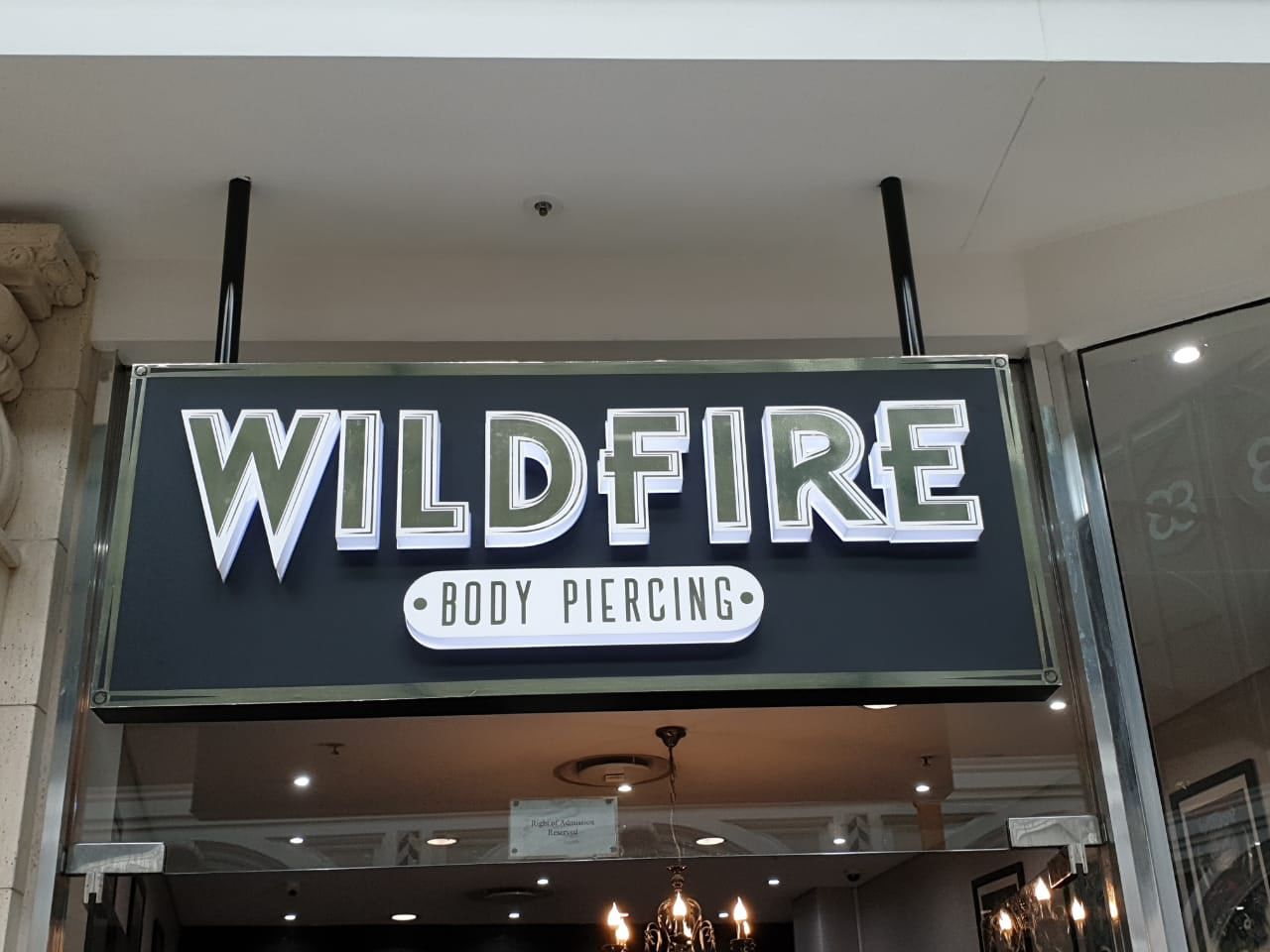 Wildfire Body Piercing sign with raised lettering above a mall shopfront