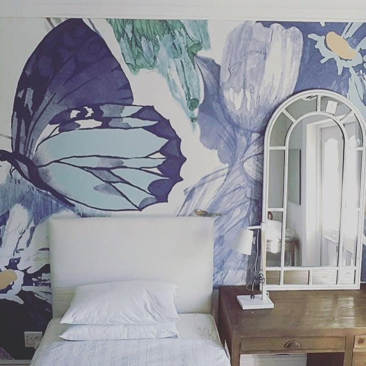 Oversized butterfly wallpaper behind a bed
