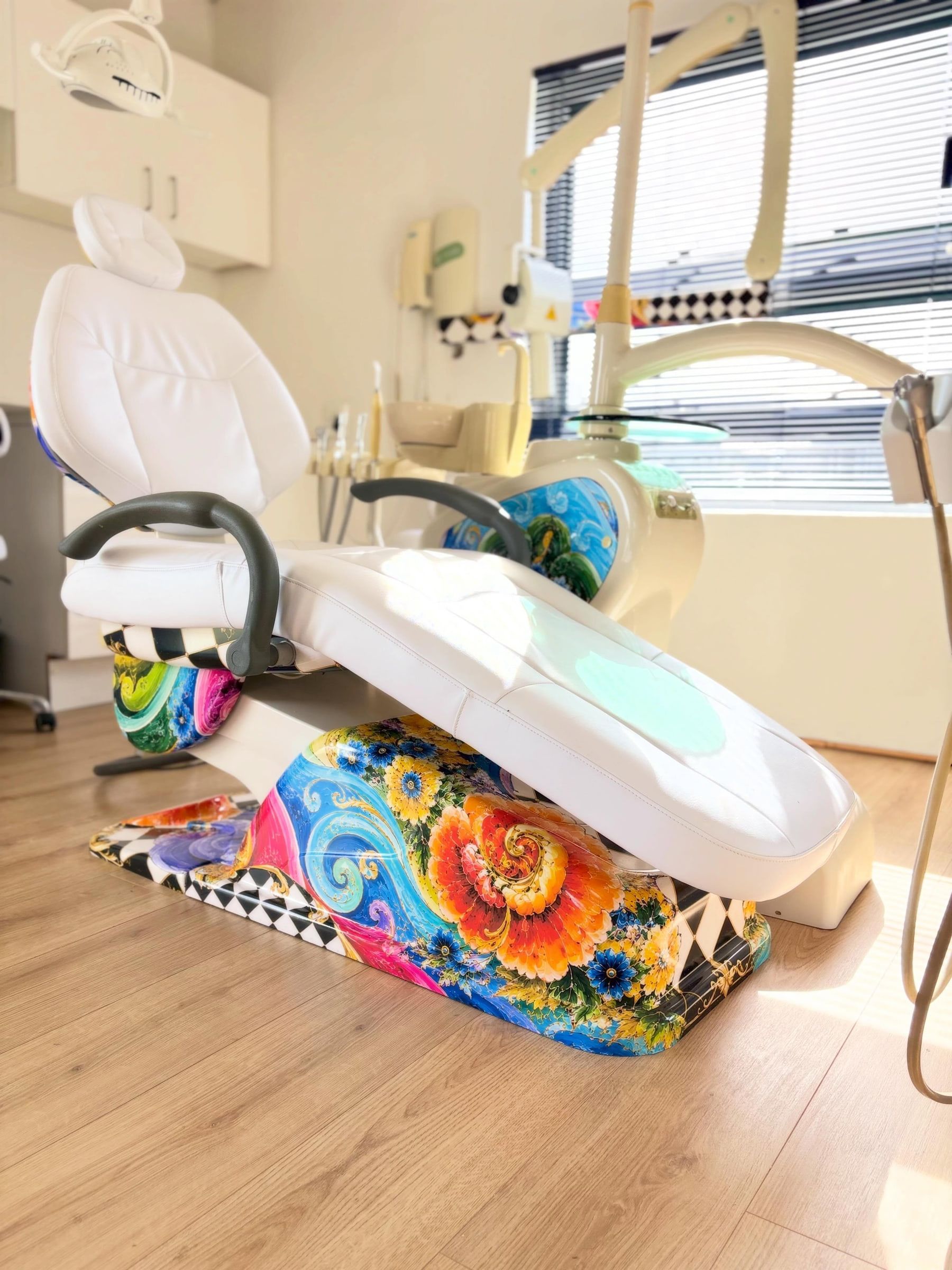 Reclined dental chair with a floral printed wrap on the base and armrests
