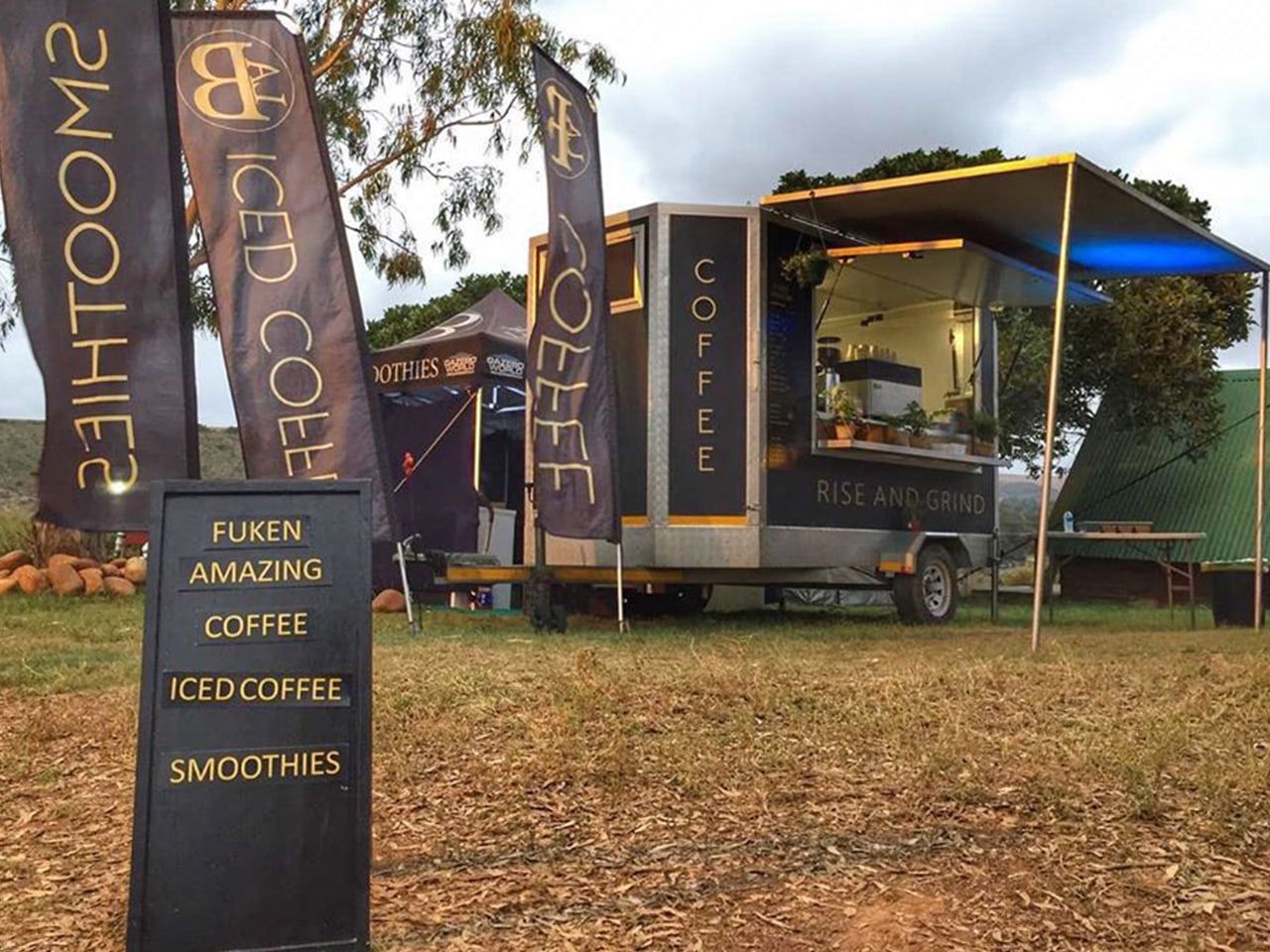 Coffee trailer with printed teardrop flags and an A-frame menu board