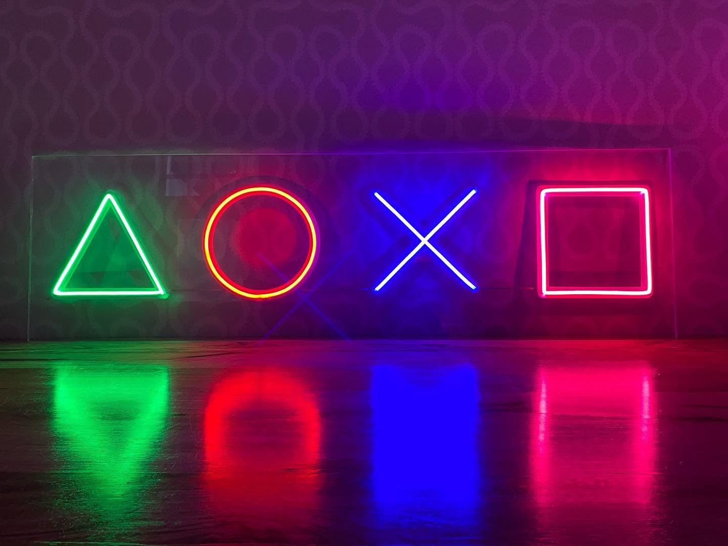 Glowing neon game controller symbols on a dark wall