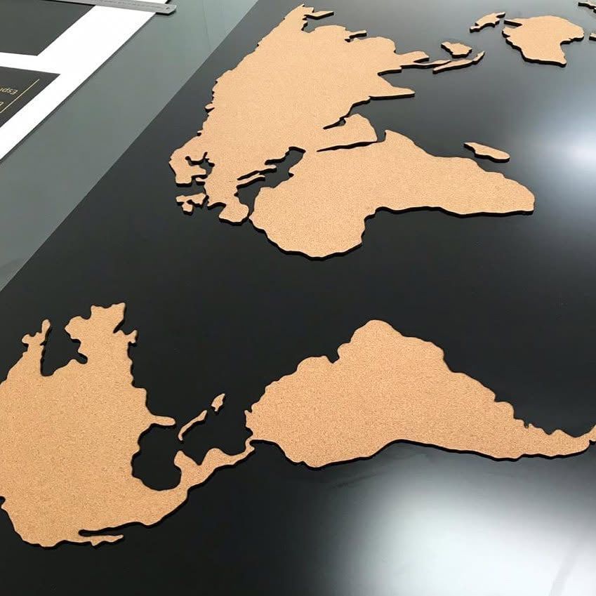 Laser-cut cork world map mounted on a black wall