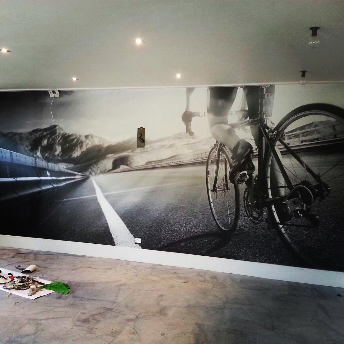 Black and white wall mural of a road cyclist at speed