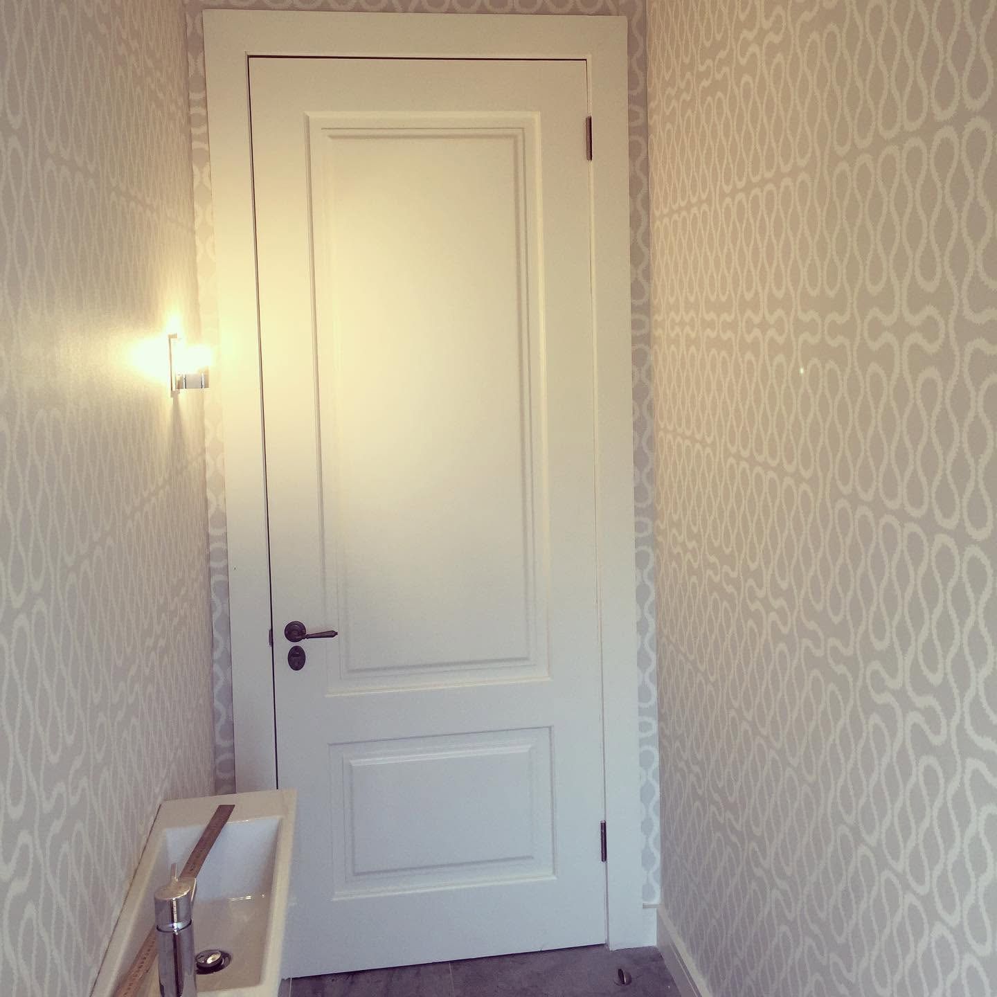 Patterned wallpaper around a white panelled door