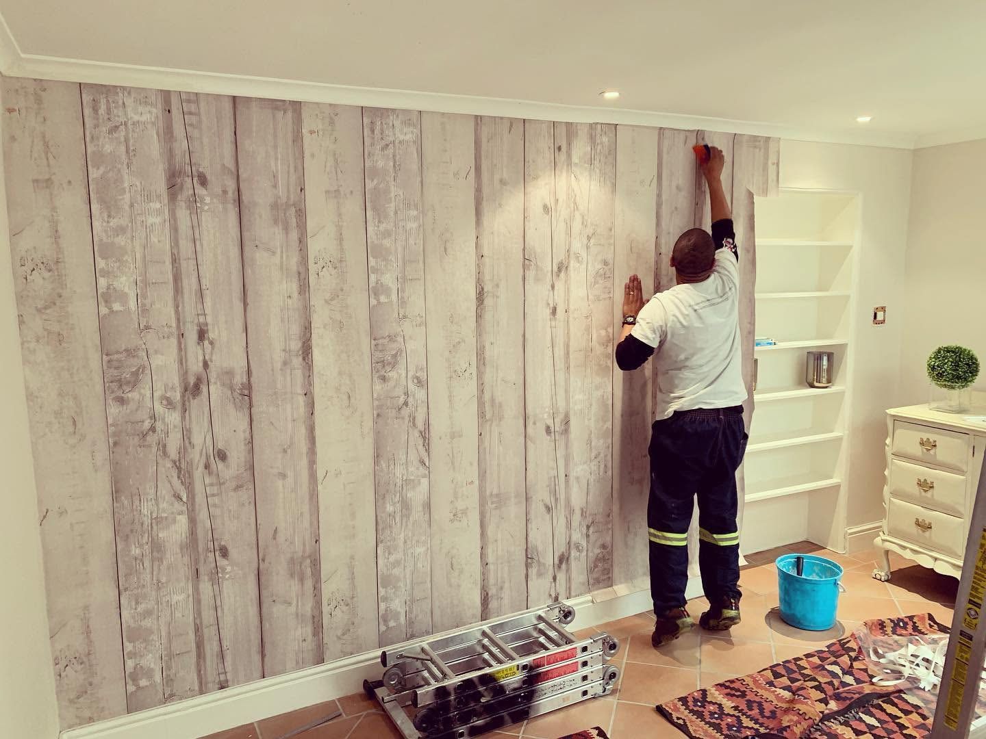 Installer hanging whitewashed wood-plank wallpaper