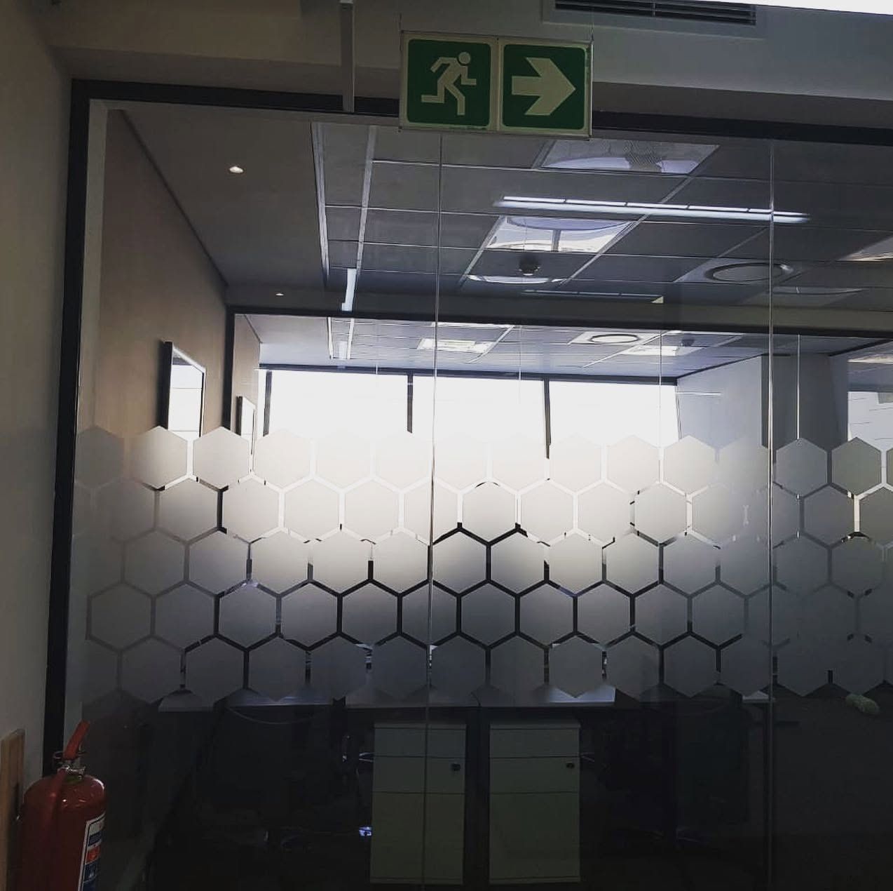 Hexagon frosted manifestation band across an office glass wall