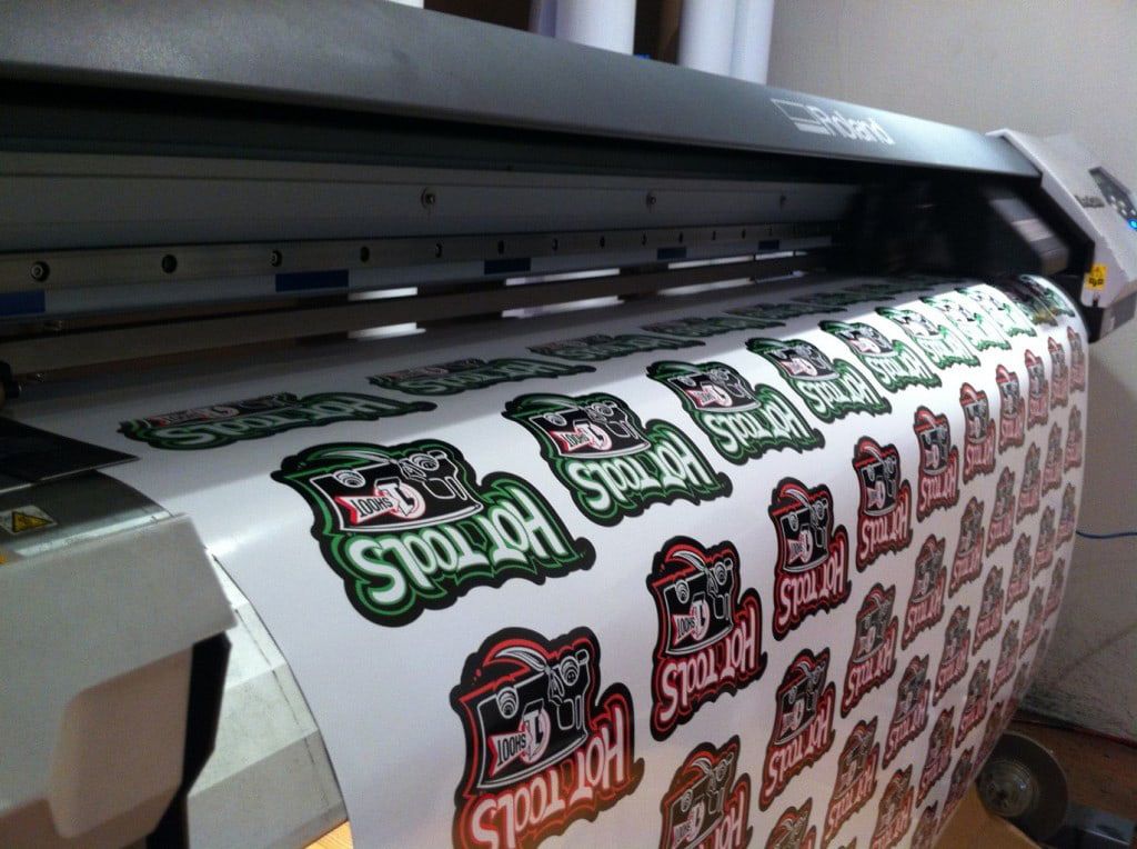 Printer-cutter printing a sheet of green and black Hot Tools logo stickers