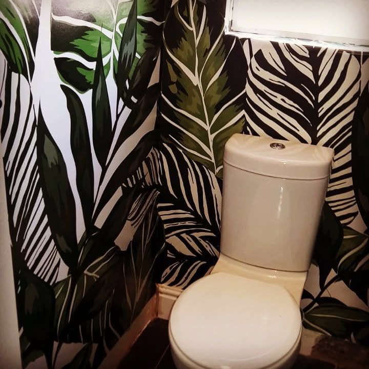 Black and white jungle leaf wallpaper in a guest toilet
