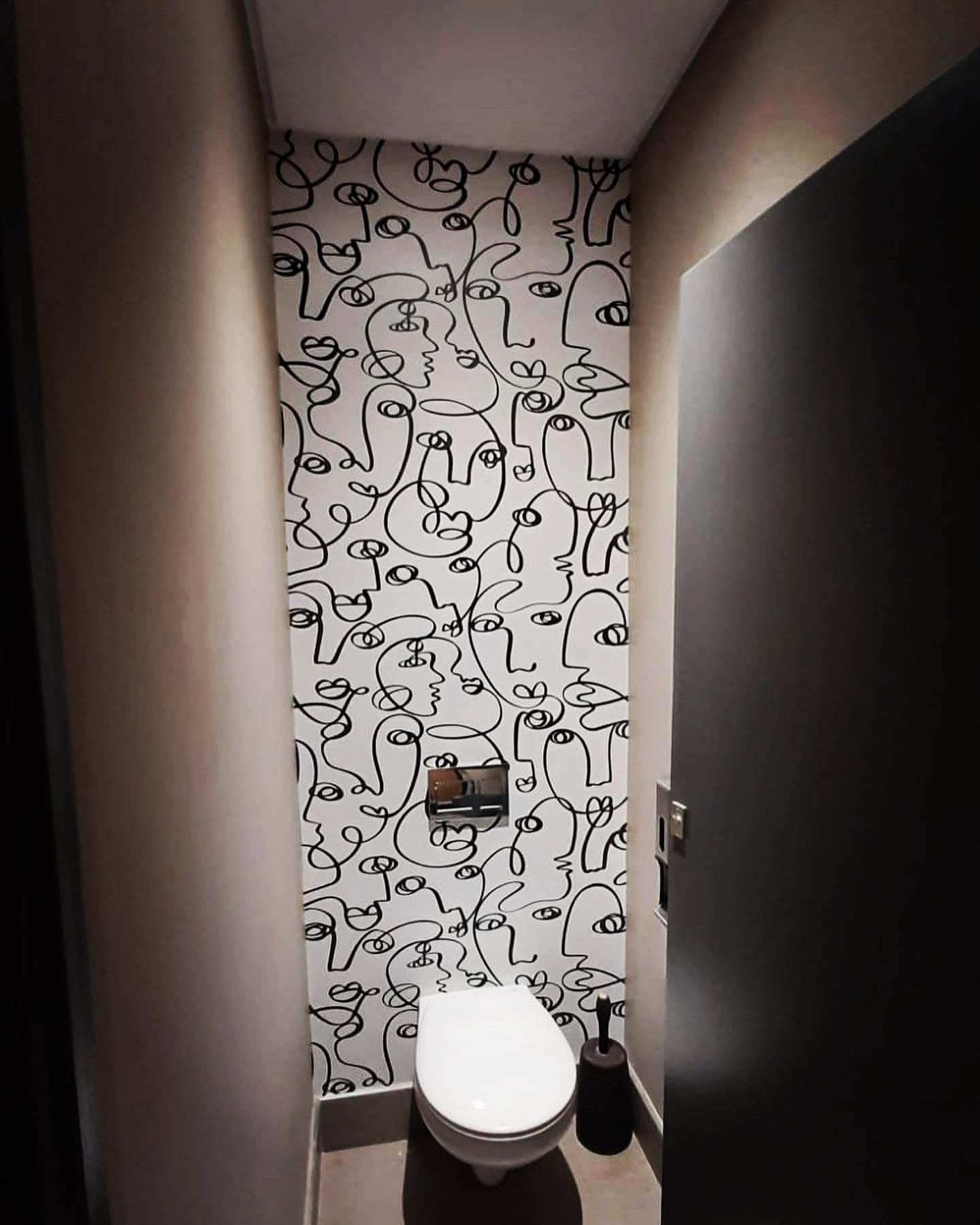 Washroom cubicle papered in a black line drawing of faces