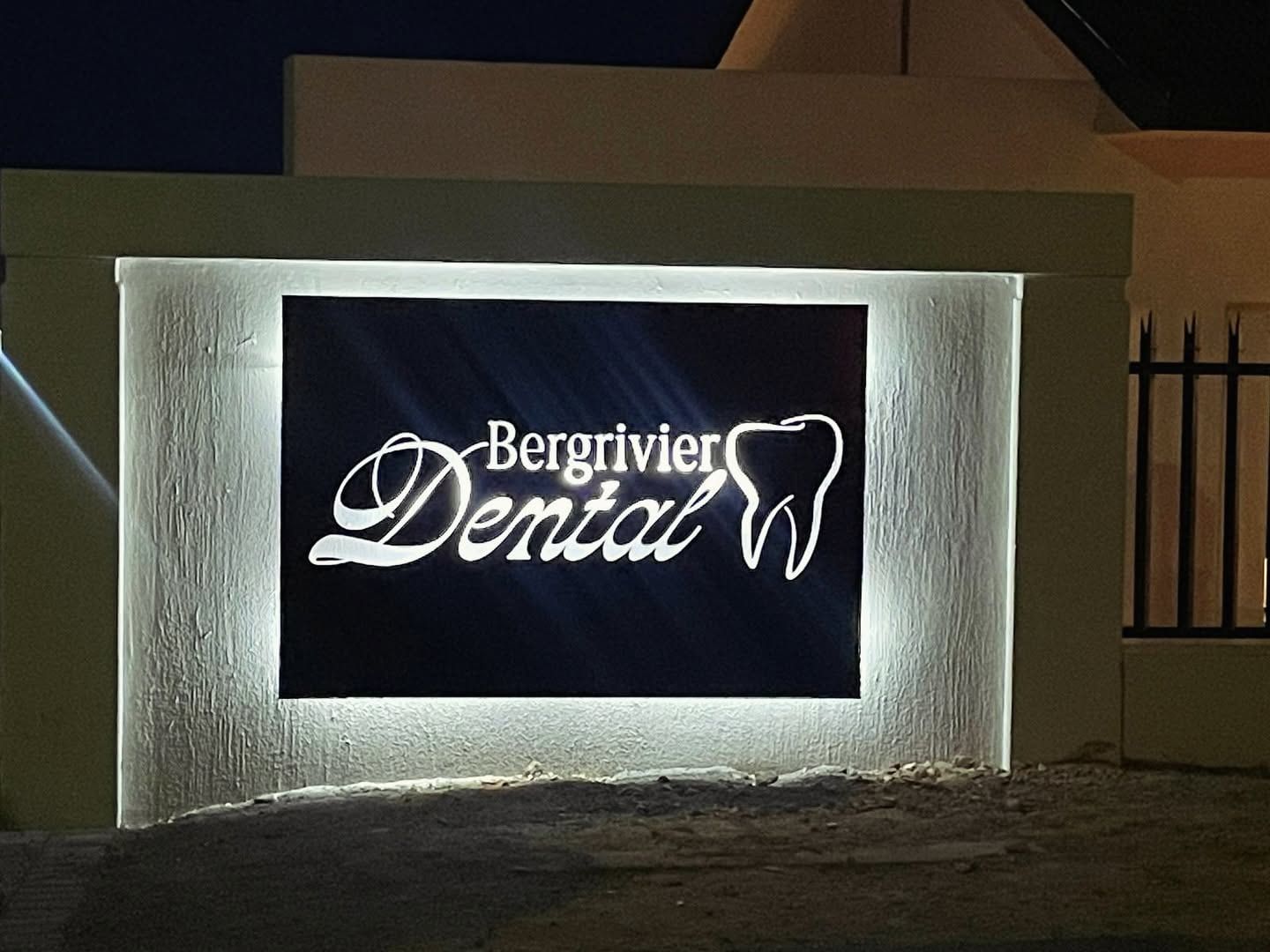 Bergrivier Dental sign glowing with a white halo on a wall at night