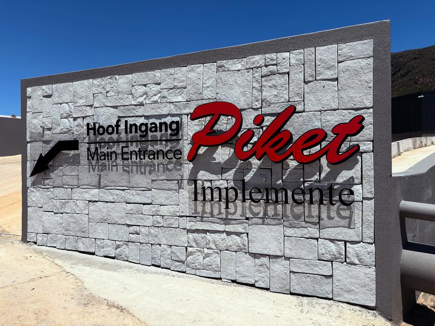 Piket Implemente letters and Hoof Ingang, Main Entrance wayfinding on a stone wall