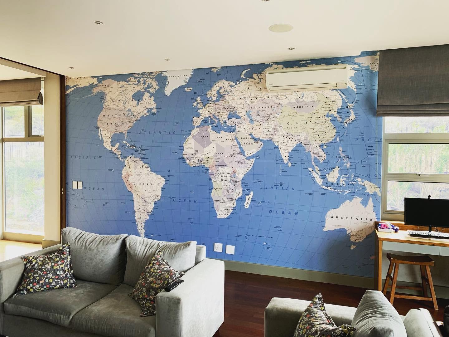 Blue world map wallpaper behind a lounge suite and desk