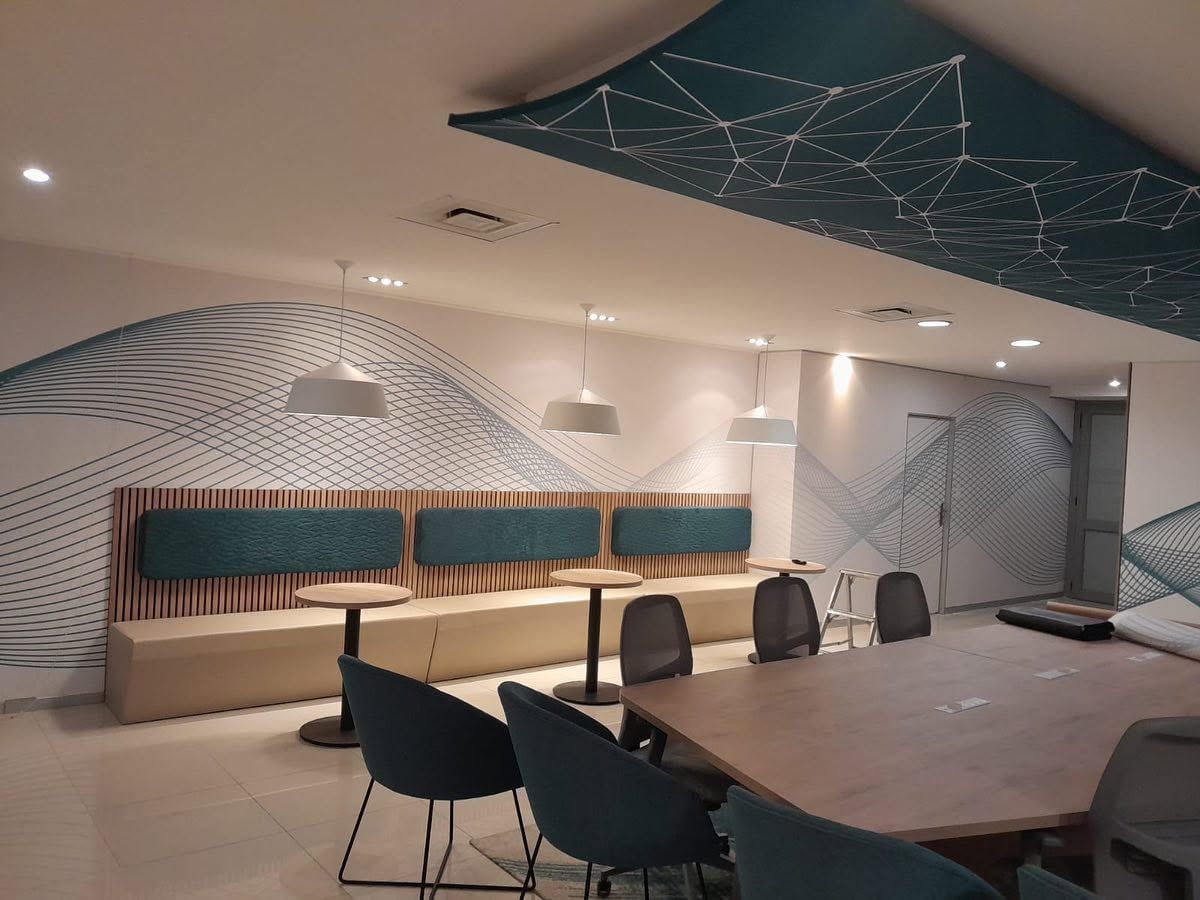Meeting tables under a teal geometric ceiling graphic