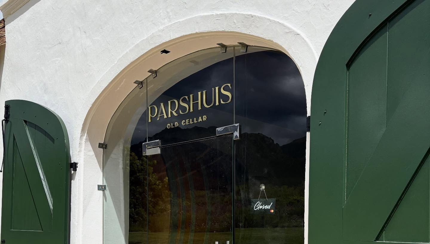Gold Parshuis Old Cellar lettering on the glass of an arched doorway with green shutters