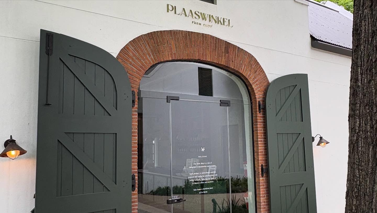 Plaaswinkel lettering above an arched brick doorway with green shutters