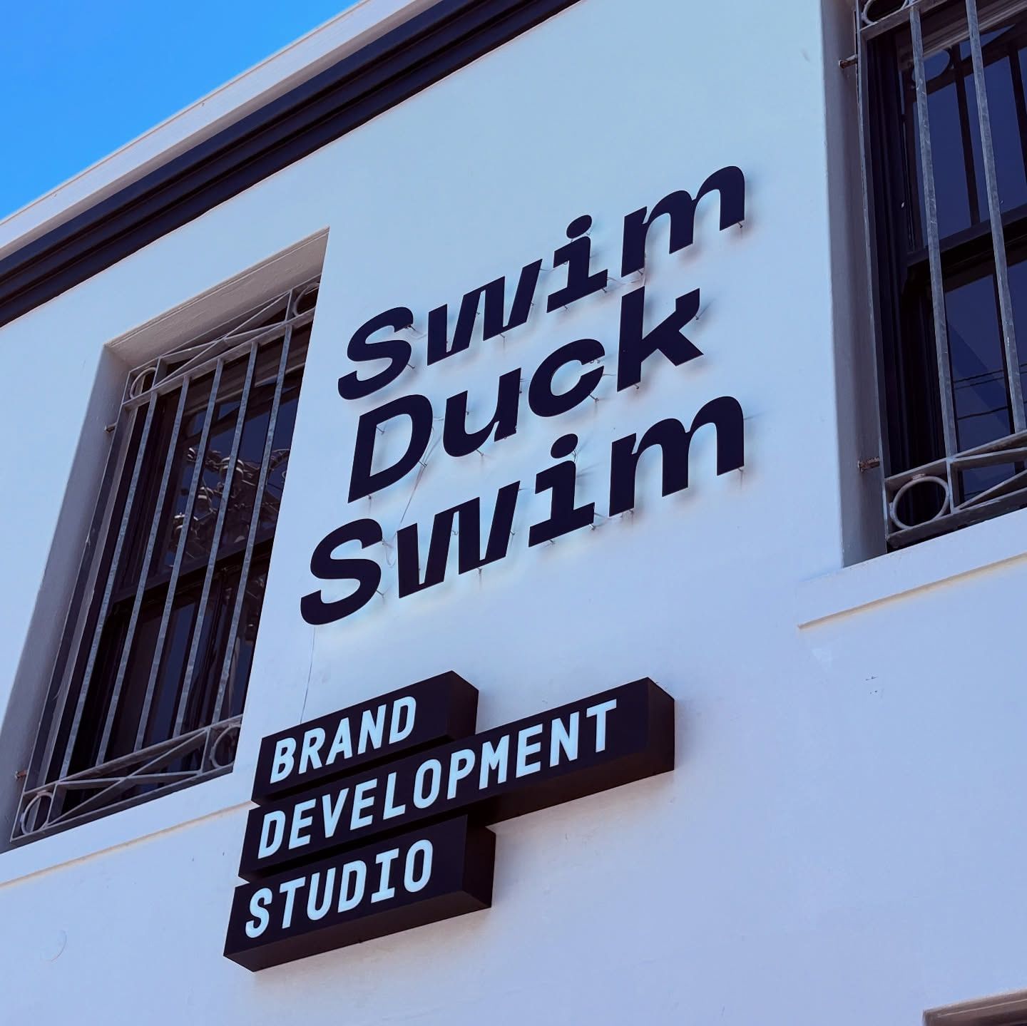 Swim Duck Swim wordmark and Brand Development Studio projecting sign on a Bo-Kaap building