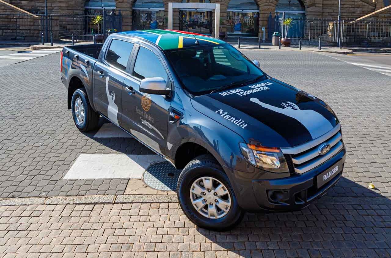 Grey Ford Ranger branded for the Nelson Mandela Foundation, with a South African flag across the roof and a raised fist graphic on the bonnet and doors
