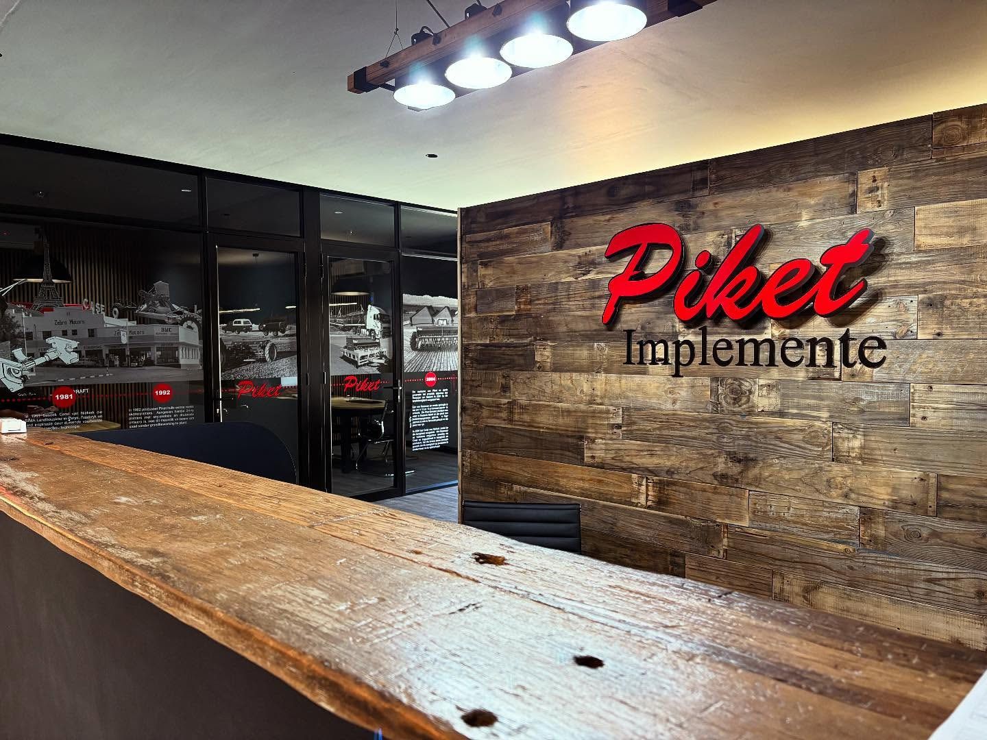 Red and grey Piket Implemente letters on a reclaimed timber reception wall