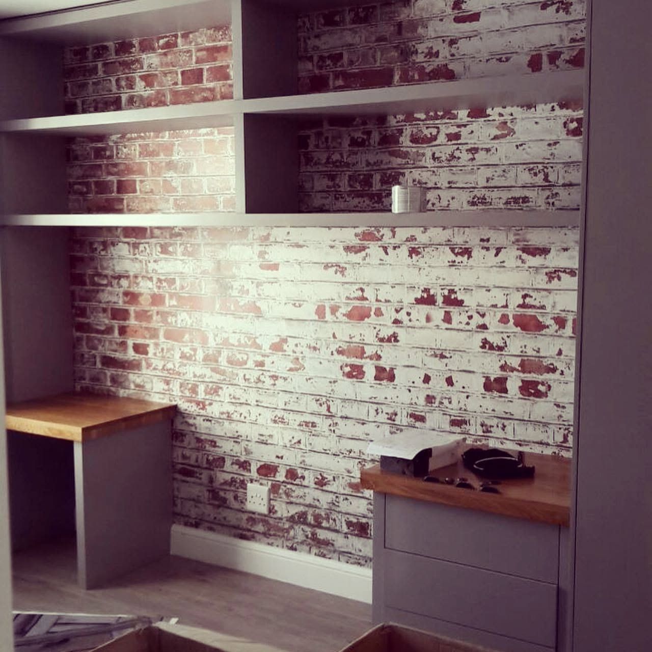 Weathered red brick wallpaper behind open shelving