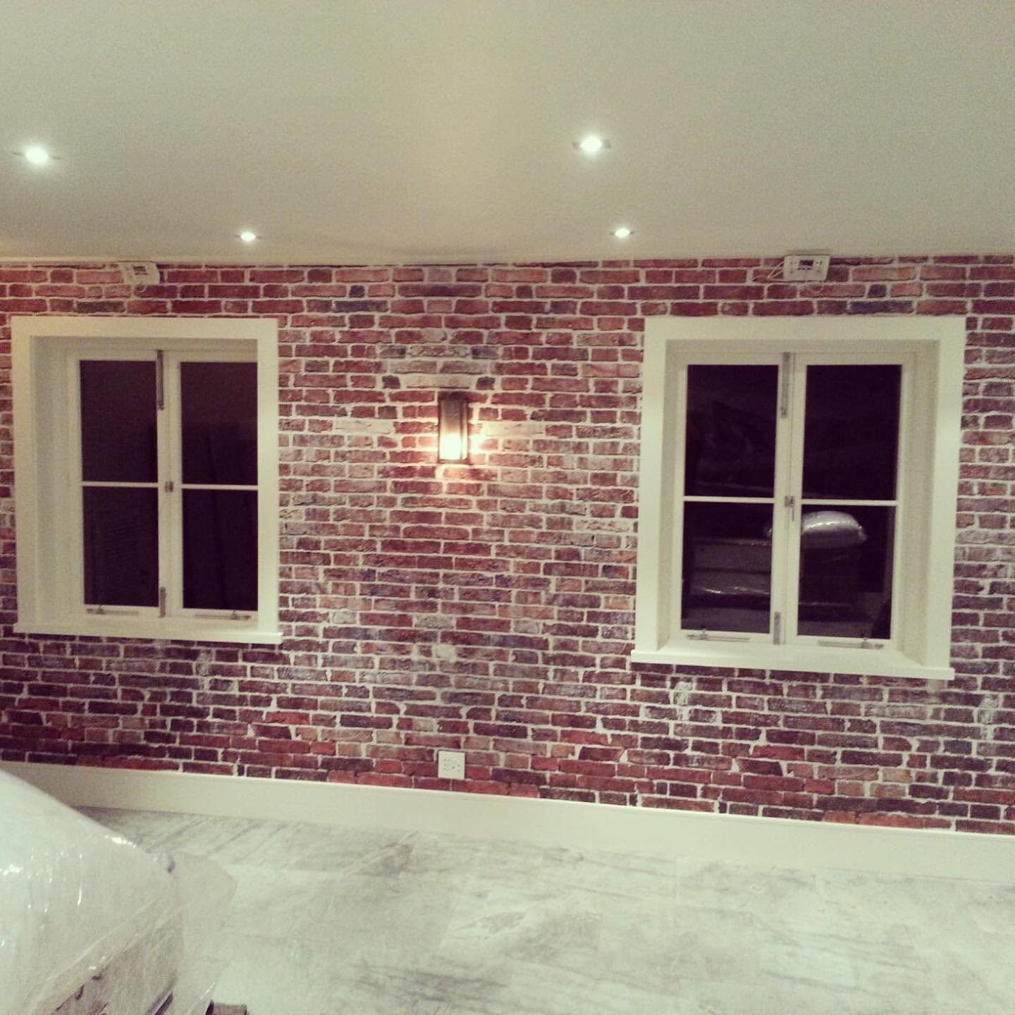 Red brick effect wallpaper between two windows