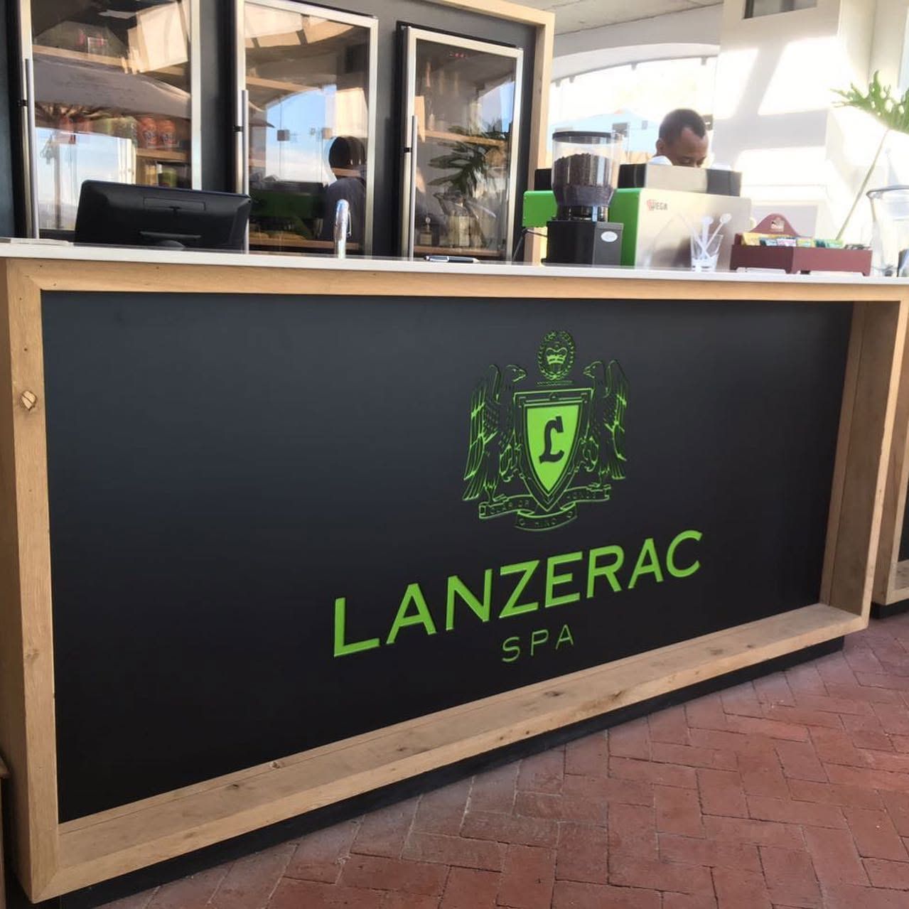 Black bar front with the green Lanzerac Spa crest in a pale timber frame