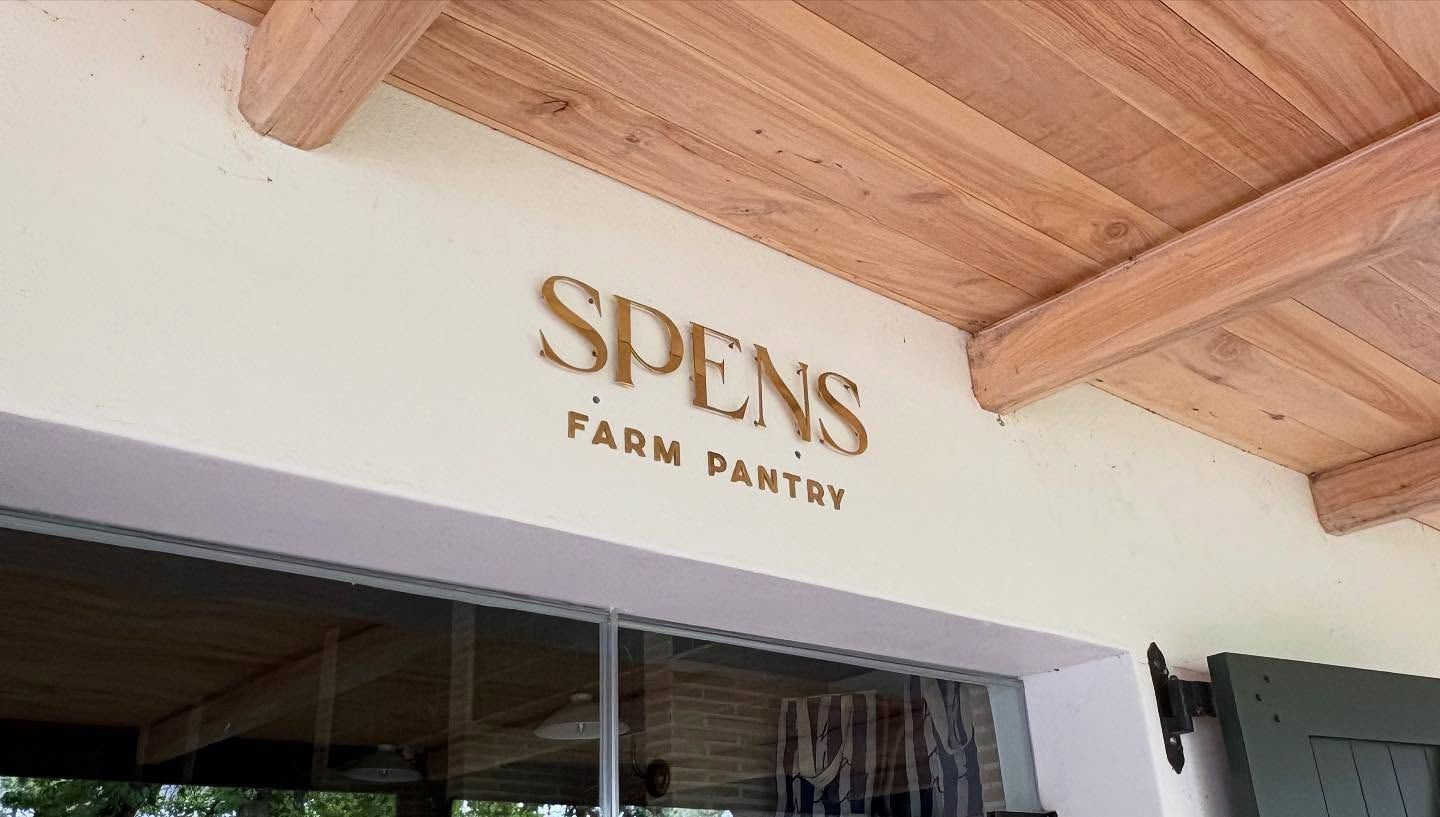 Spens Farm Pantry lettering in gold on a white wall under a timber pergola