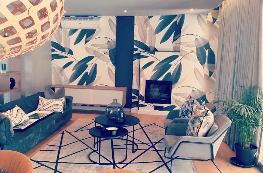 Large tropical leaf wallpaper behind a lounge
