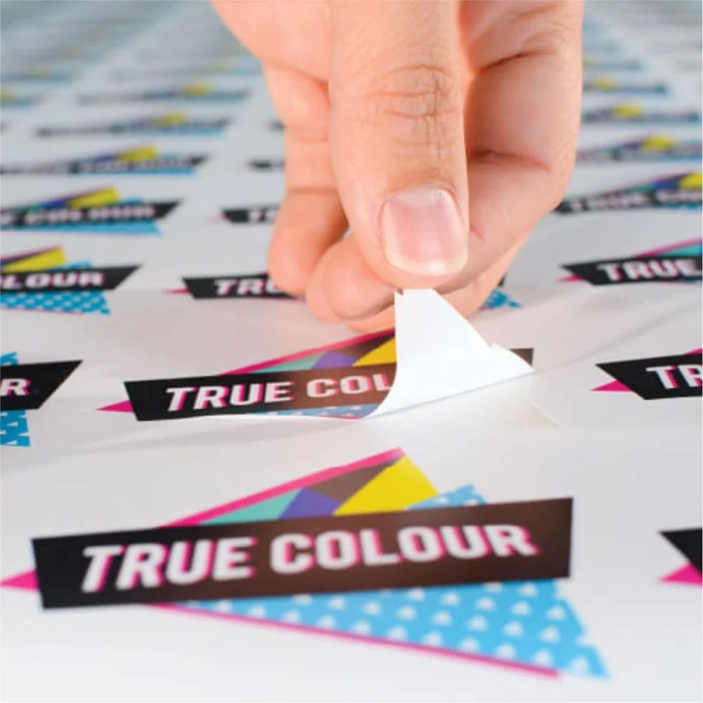 Hand peeling a printed True Colour sticker off its backing sheet