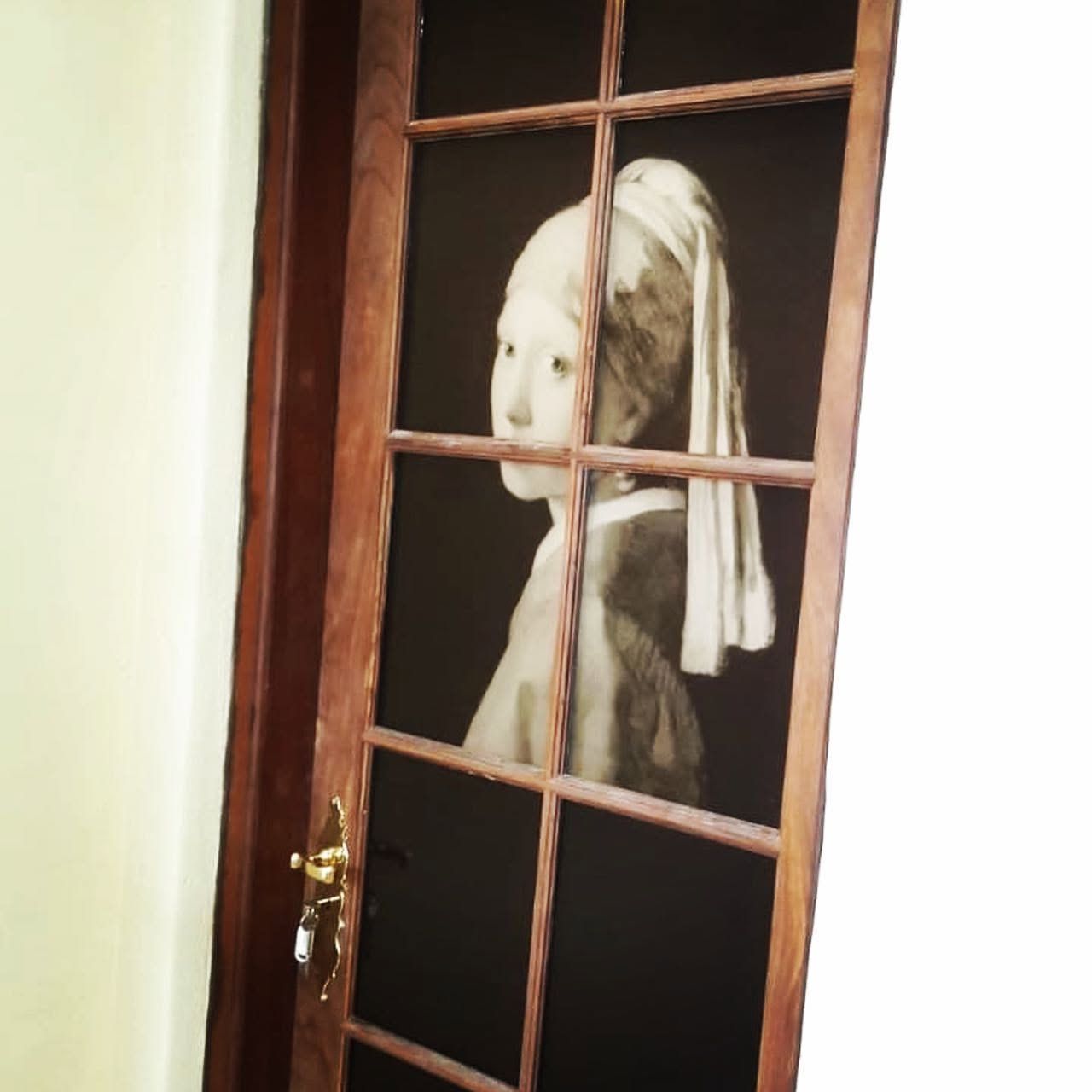 Girl with a Pearl Earring printed across the panes of a wooden glass door