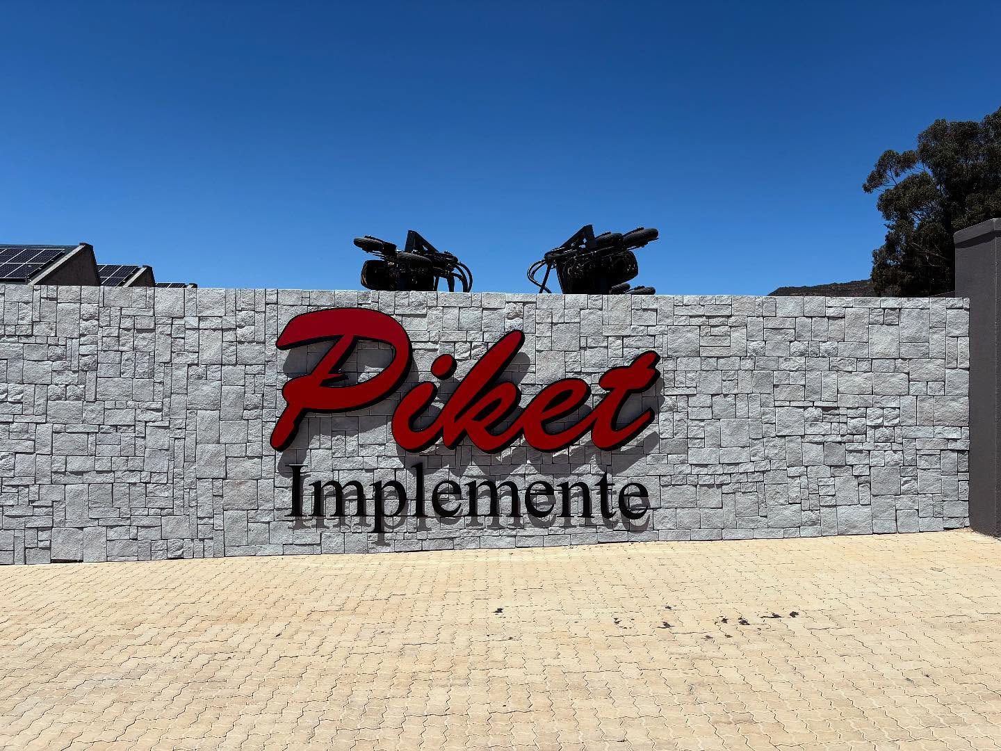 Long stone boundary wall with Piket Implemente lettering in Piketberg