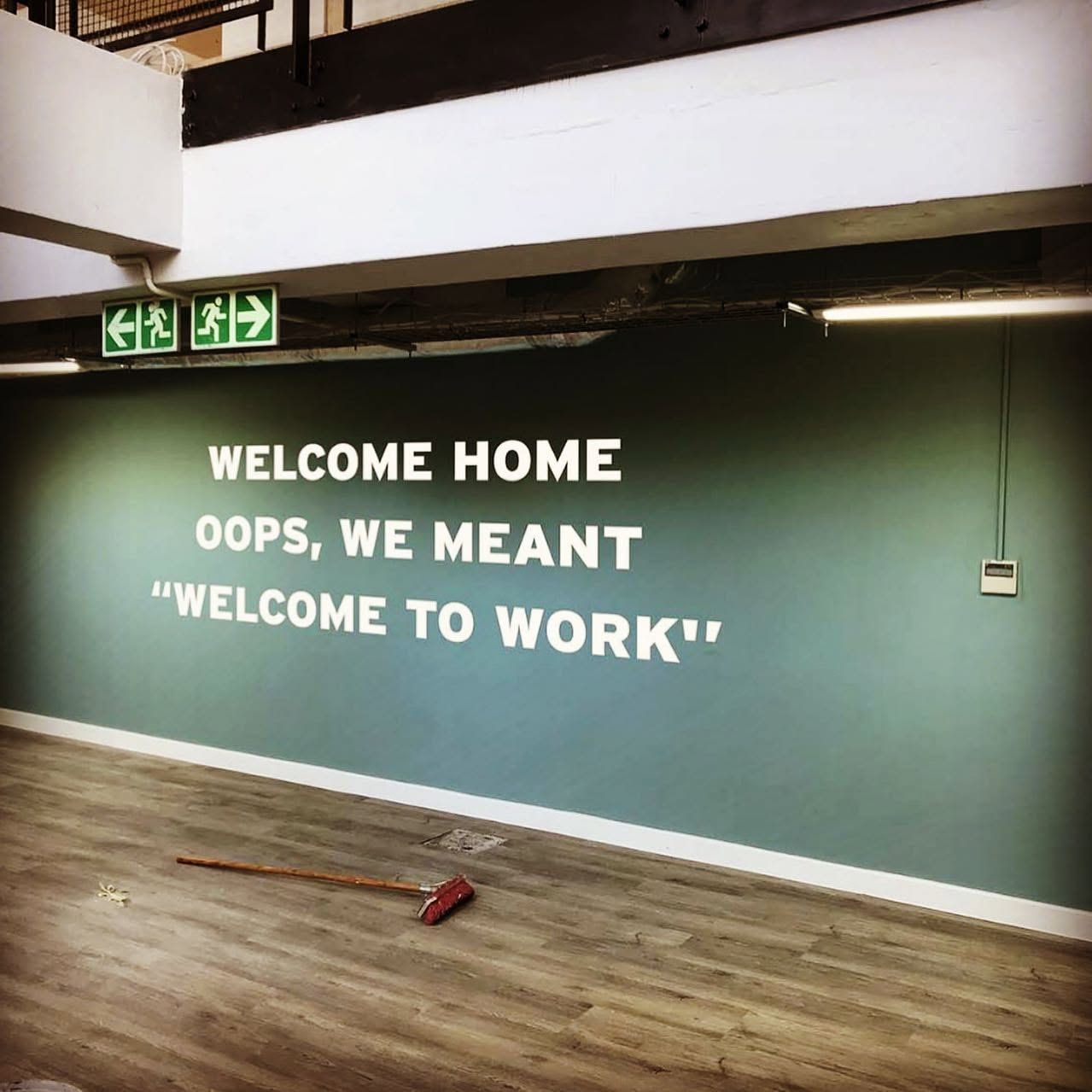 Office wall lettering reading Welcome home, oops, we meant welcome to work