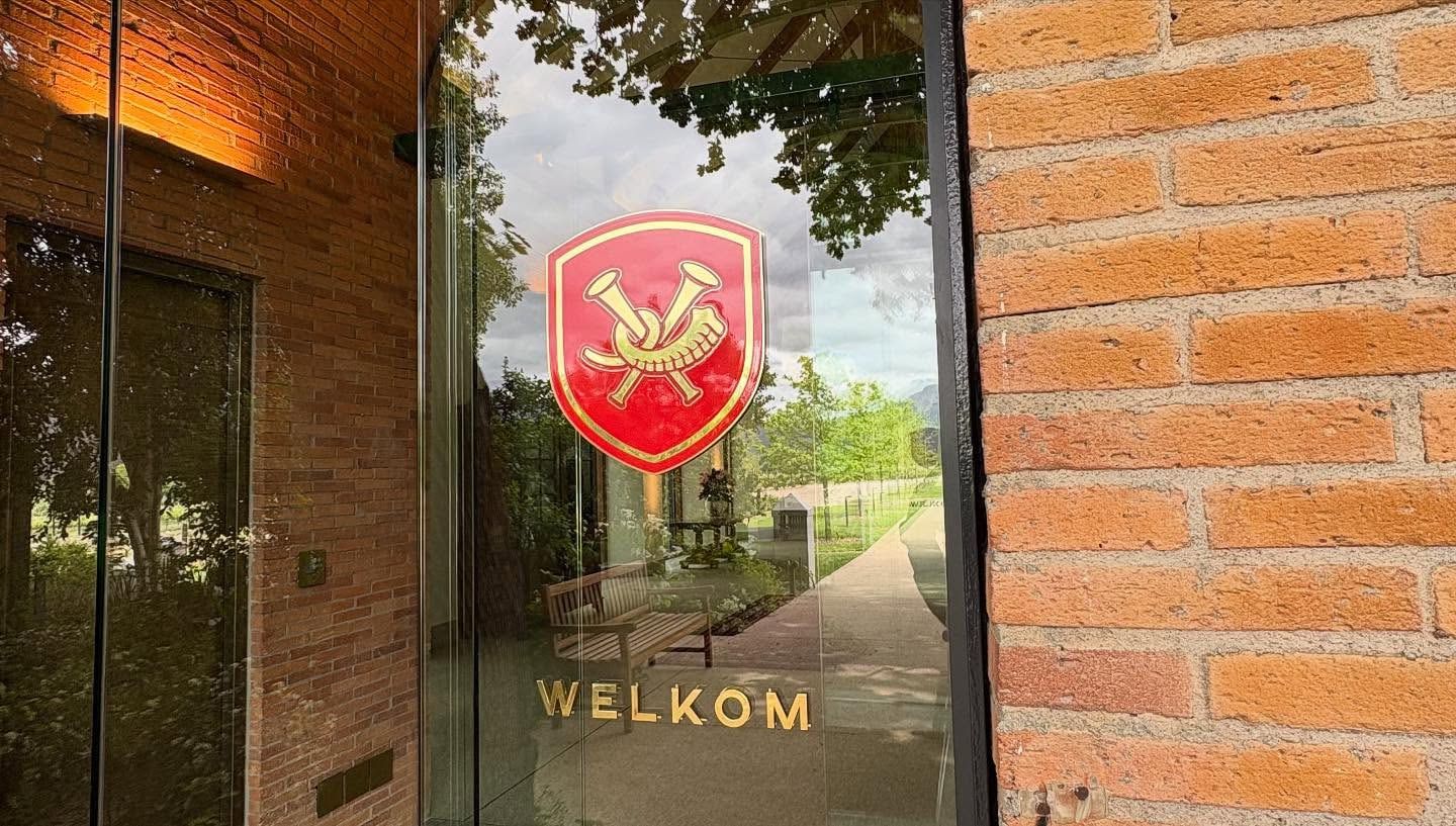 Red crest and Welkom lettering on a glass door set into a brick wall