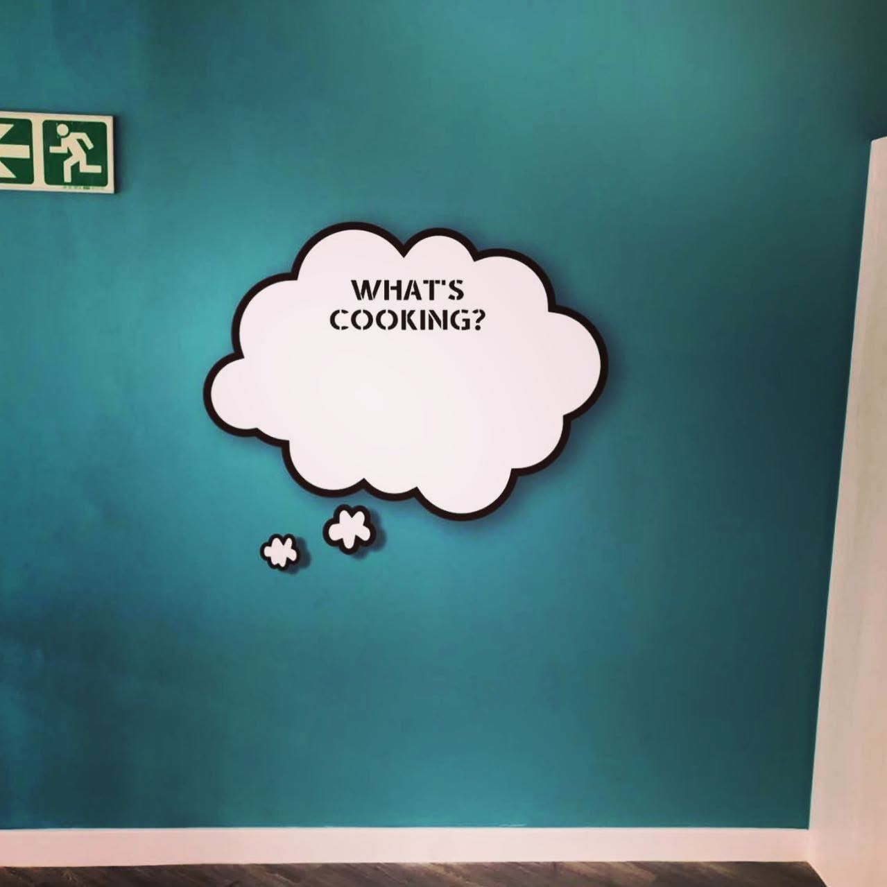 Speech bubble decal reading What's cooking on a teal kitchen wall